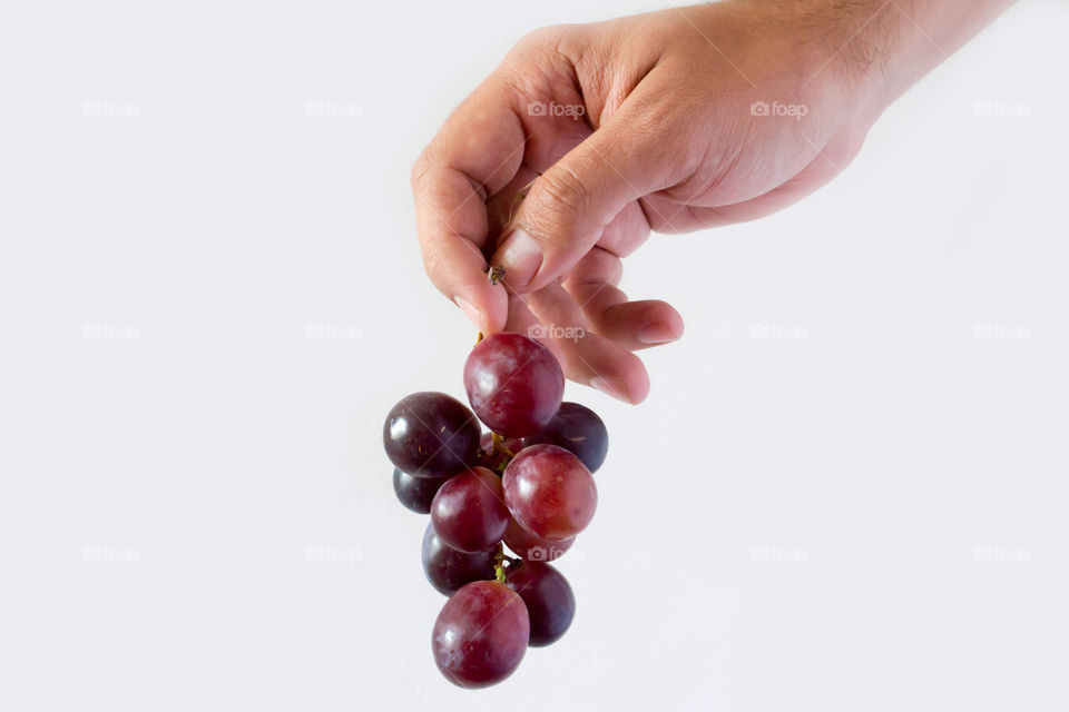 A hand holding a branch of grapes