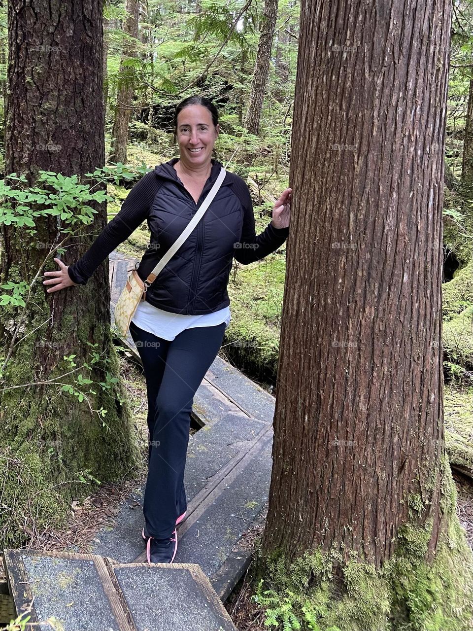 While hiking in an Alaskan forest, a fabulous ex dancer mom strikes a pose between two trees.