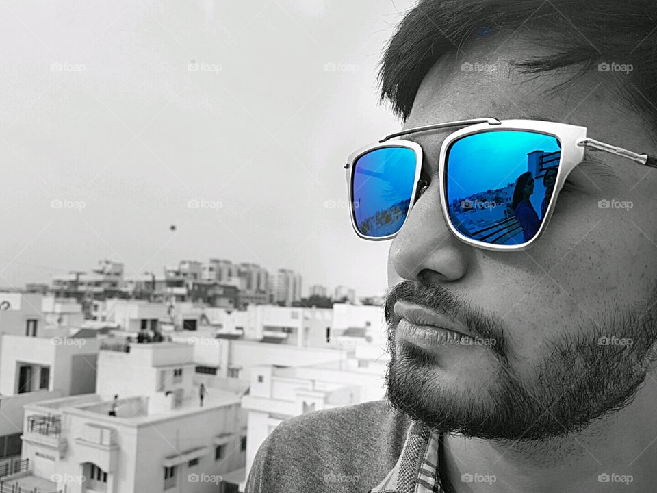 An Indian young man wearing blue sunglasses