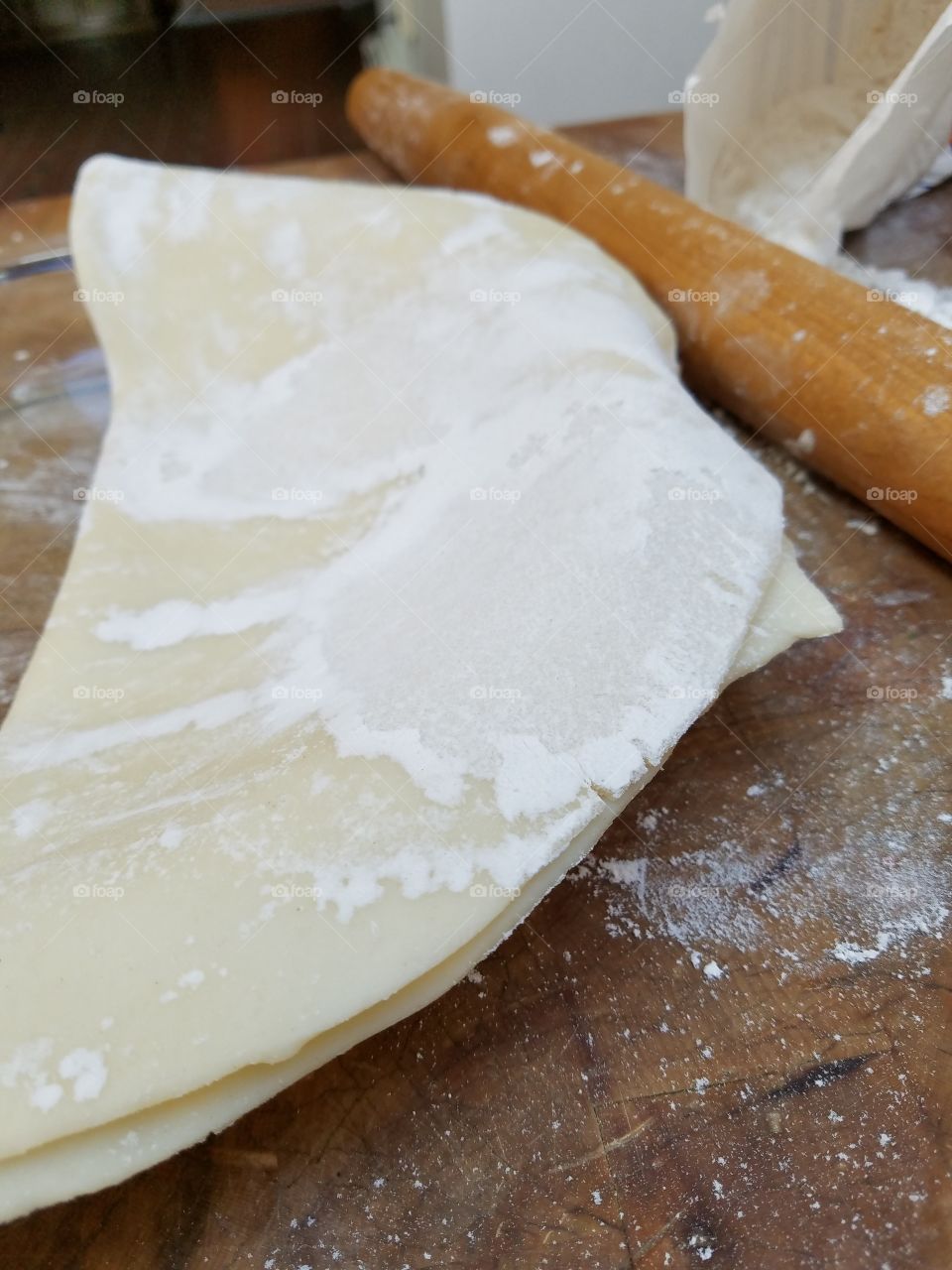 One crust pie shell folded, old wooden rolling pin, clear glass pie plate.
