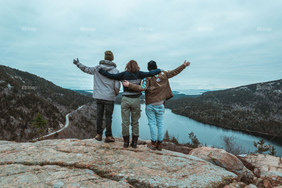 Three friends stand on top of a mountain range 