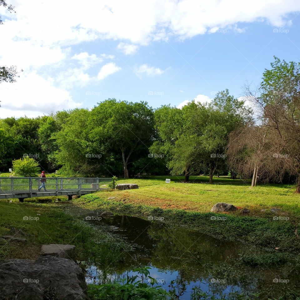 City park with a metal bridge over a creek.