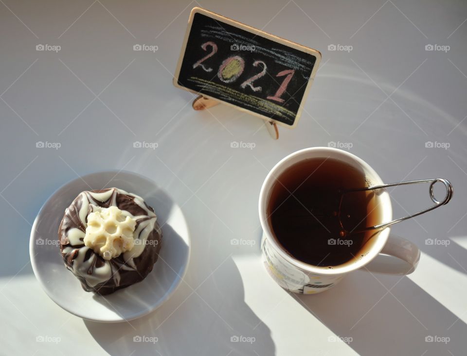 cup of tea with chocolate cake tasty and wooden board 2021 top view on a white background, cozy winter, New year 2021