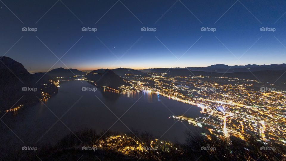 Night panorama of Lugano. Sunset over Lugano, with the city lights reflecting in the lake
