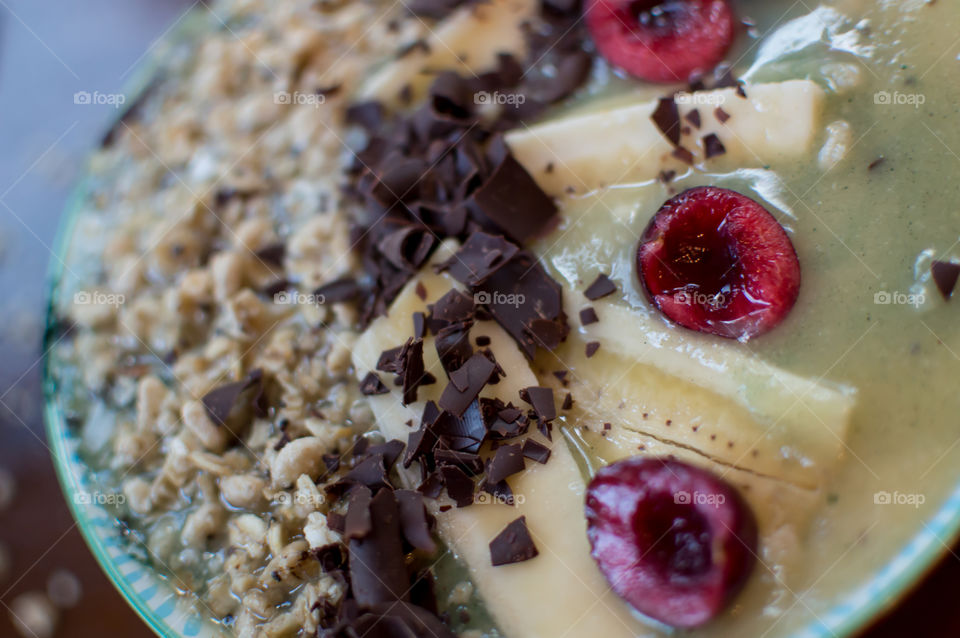 Closeup fresh fruit smoothie bowl with decadent dark chocolate, black cherries, banana, granola and almonds in coconut smoothie