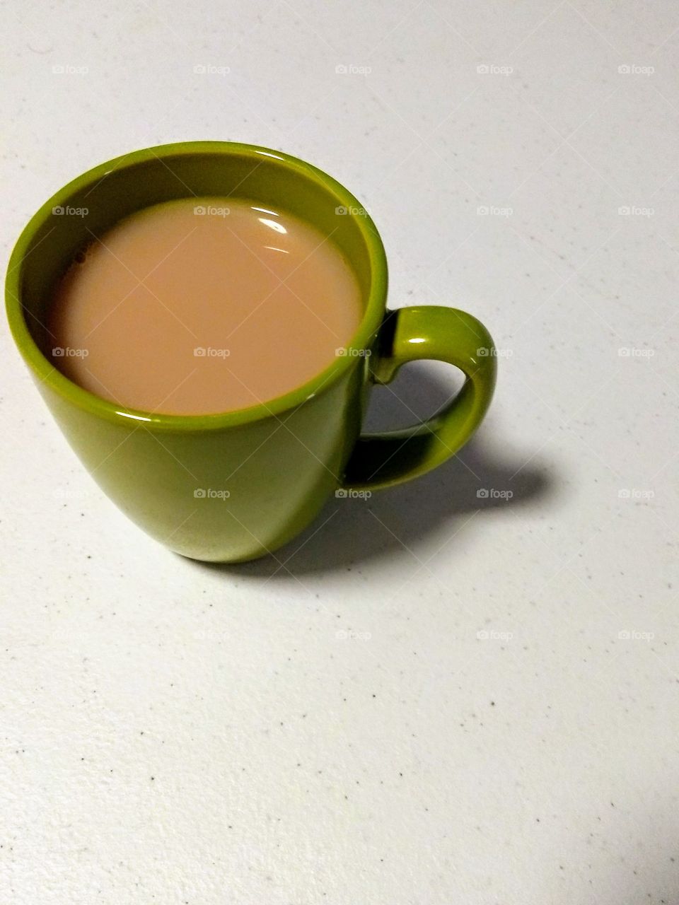 green mug of milky tea on white background