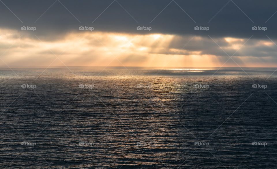 Dramatic sun rays breaking through thick clouds. Taken on a beach in San Diego CA.