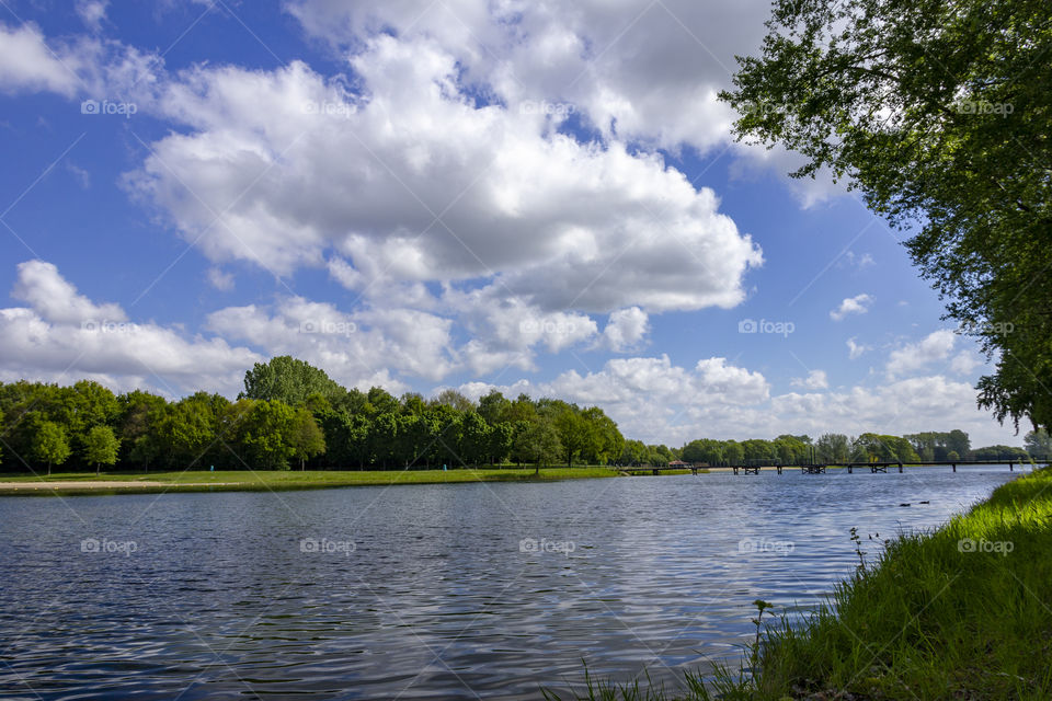 A portrait of the lake at Bussloo in Holland. the lake is qurrounded by a forest and has a bridge to cross it quickly.