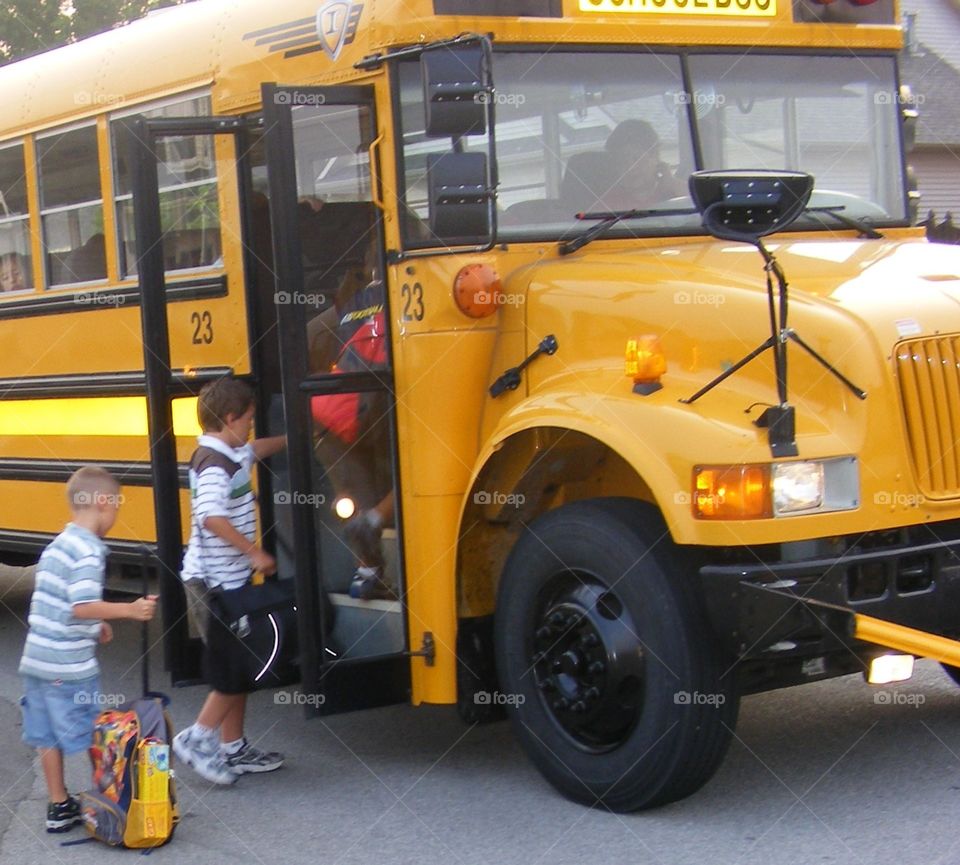 Two boys getting on the school bus.