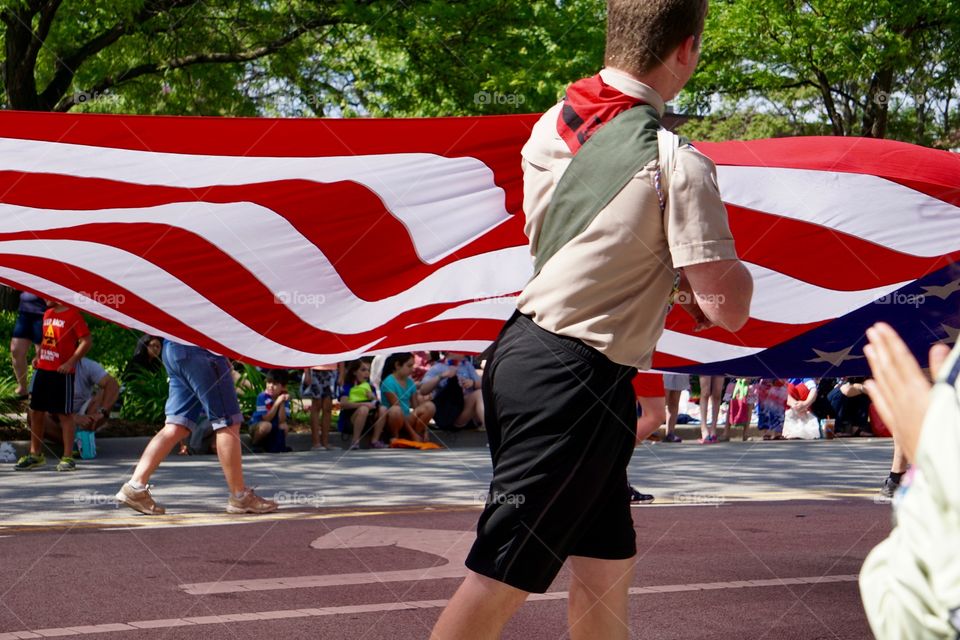 Boy Scout pulls on large American flag in parade