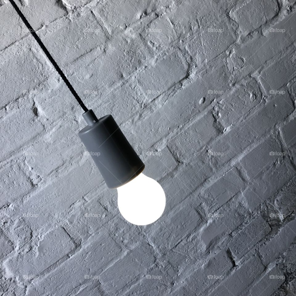 Single light bubl against white brick wall
