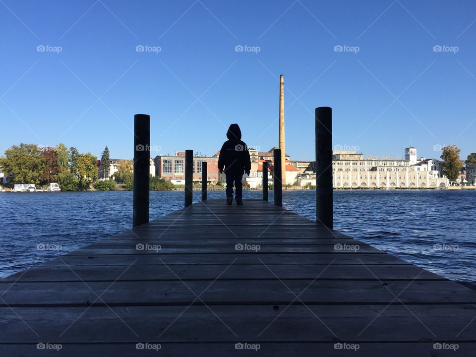 Young boy standing on a jetty. Young boy standing on a jetty in autumn coat