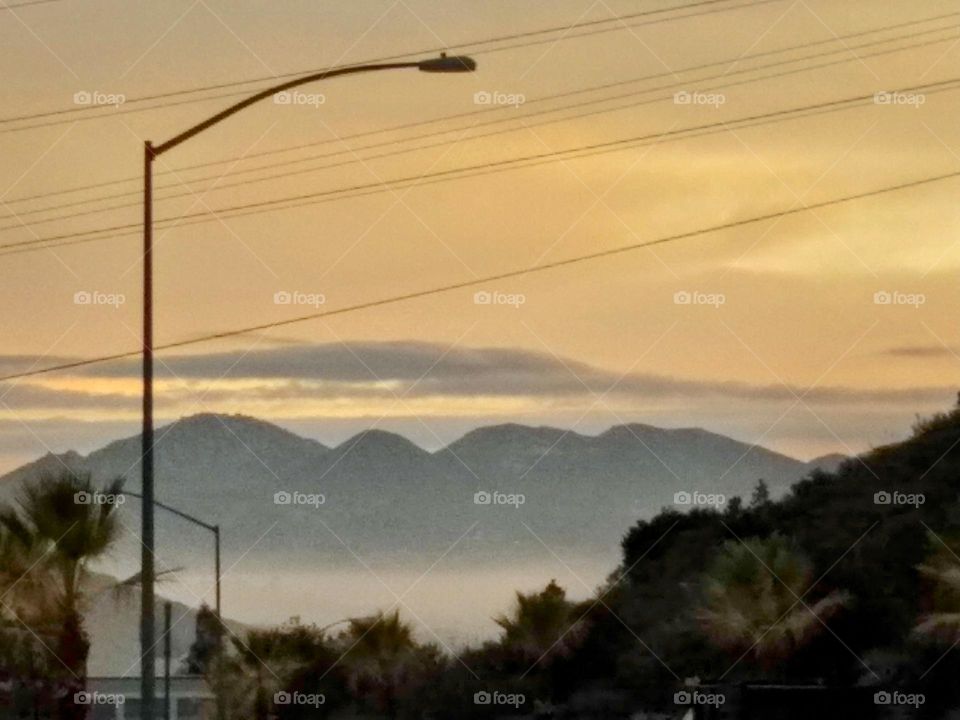 Early morning mist enshrouding the valley. Overlooking the City of El Cajon in the early dawn, with the mountains of the San Diego Backcountry in the distance. El Cajon - "The Box" in Spanish - is completely encircled by foothills.