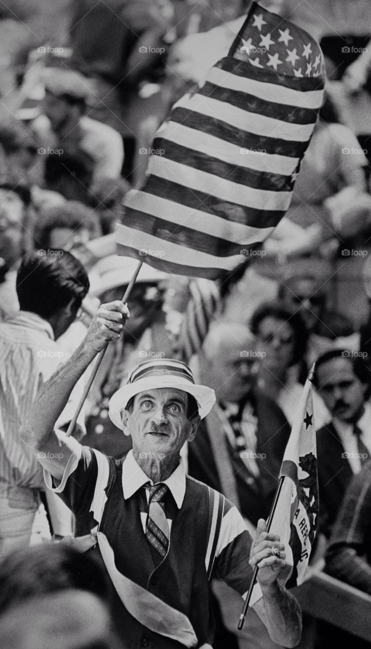 old man waves american flag. political rally usa flag waiving. by arizphotog