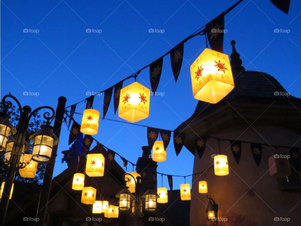 Golden lights hanging on warm summer night with dark blue sky in background 