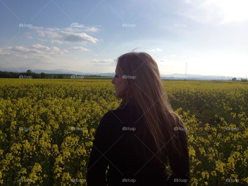 A girl portrait in the field of flowers from the back 