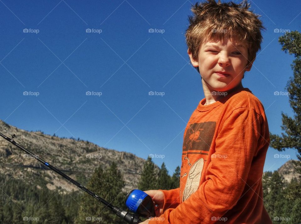 Young Boy Fishing On A Mountain Lake. Boy Fishing During Summer Vacation
