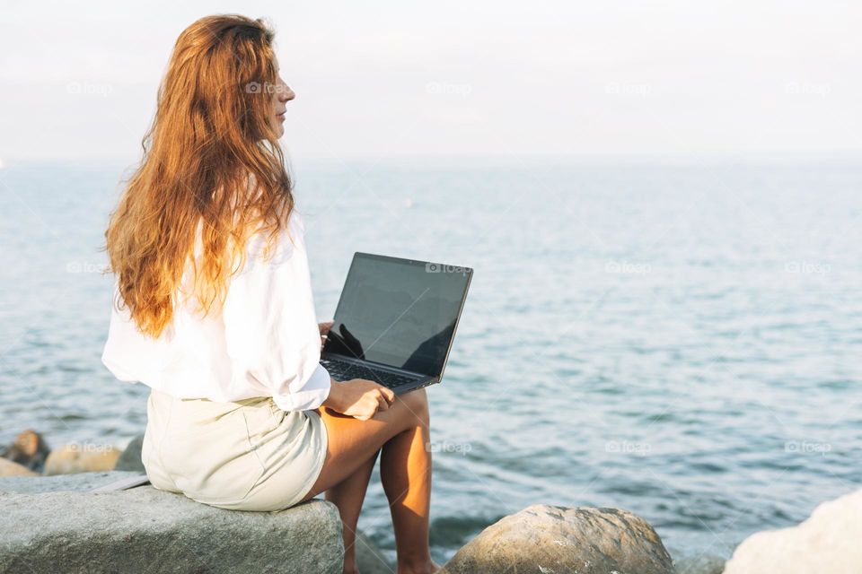 Young woman freelancer with notebook on sea beach