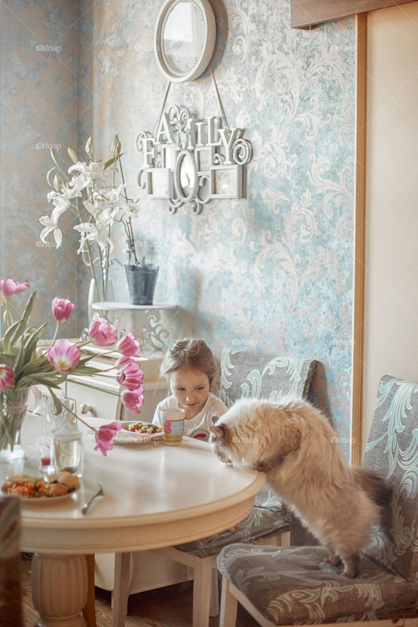 Little girl eating her breakfast in a light kitchen 