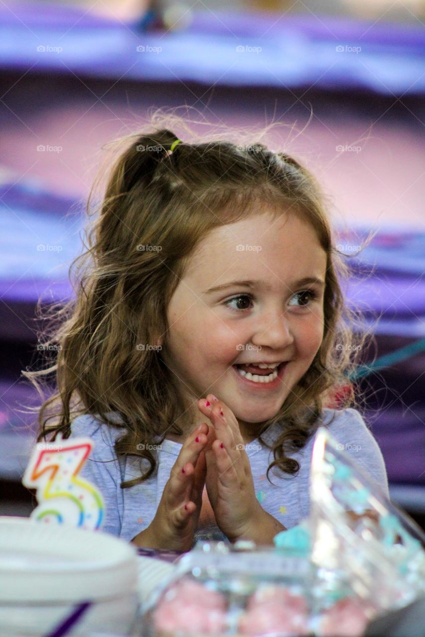 Happy toddler making a wish on her third birthday at her mermaid birthday party 