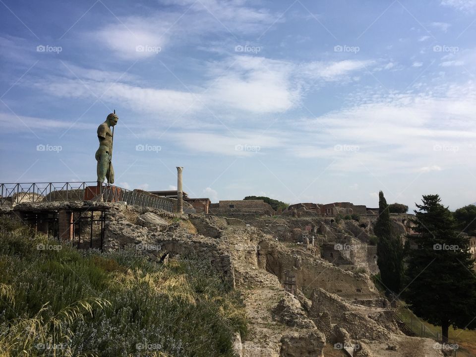 Bronze statue of Apollo on a hillside at the edge of the ruins of Pompeii 