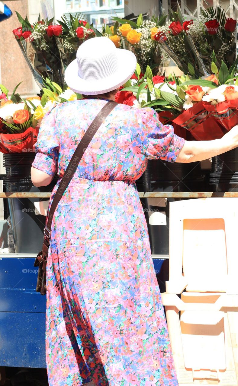 A female figure stands in front of a vibrant selection of flowers at a flower stand in city centre