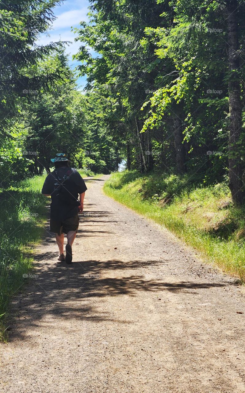 man hiking a trail through shady trees on a spontaneous day trip through an Oregon nature park