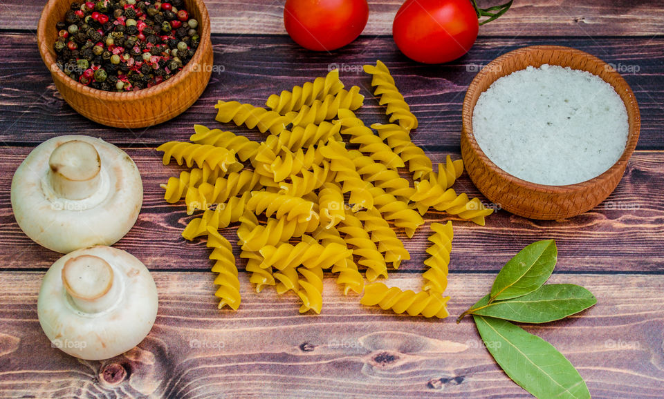 Raw pasta with ingredients and wooden accessories