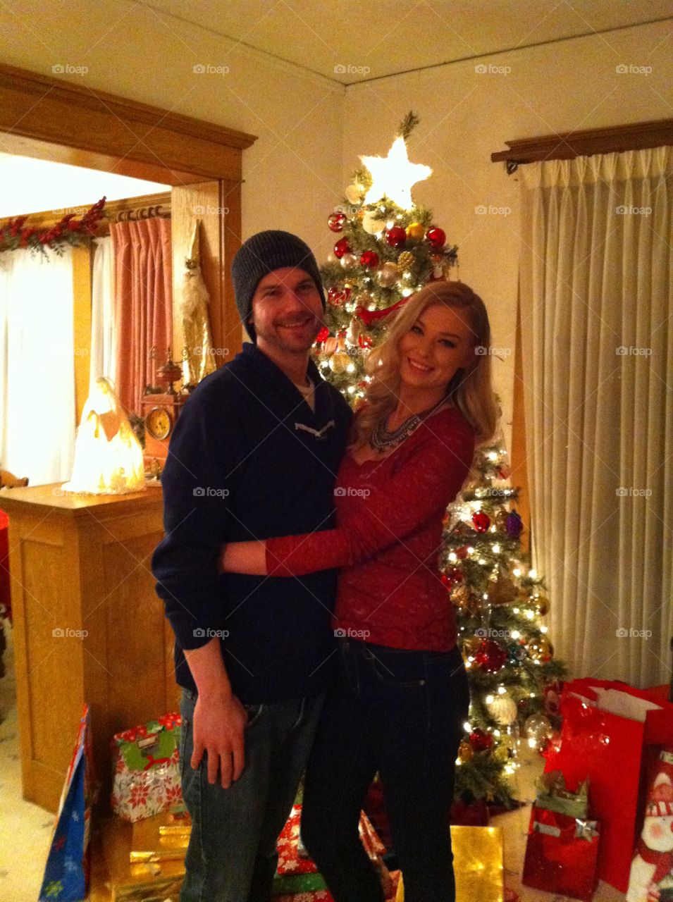 Couple standing in front of christmas tree at home