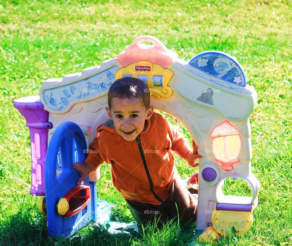Boy playing with toy house in grass