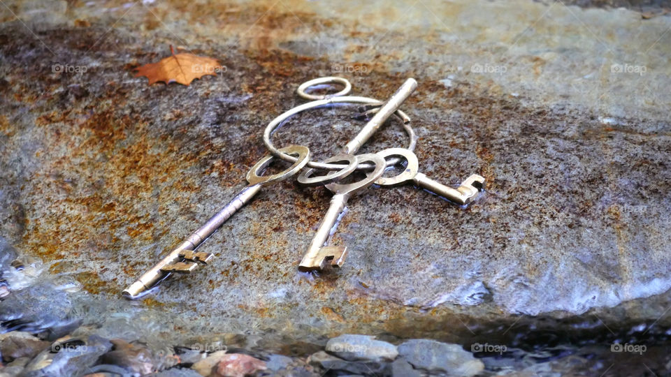Ring Of Old Brass Keys On A Wet River Rock