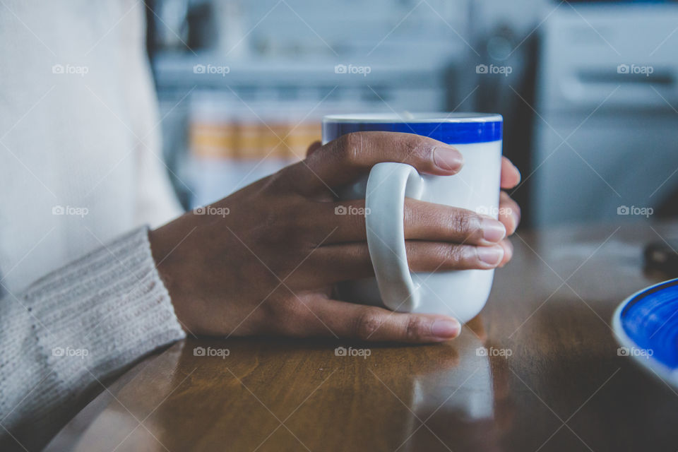 Closeup of hands with rings holding a blue mug