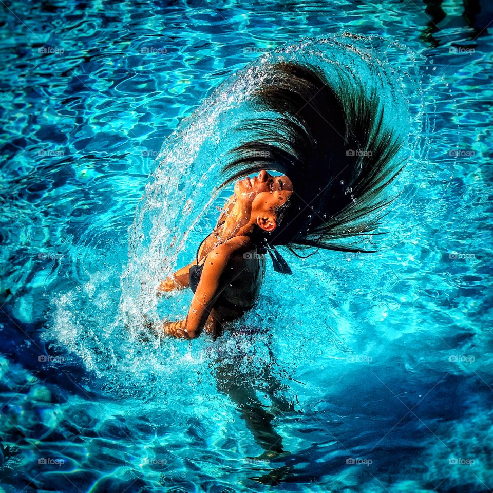 Woman splashing water with her hairs in pool