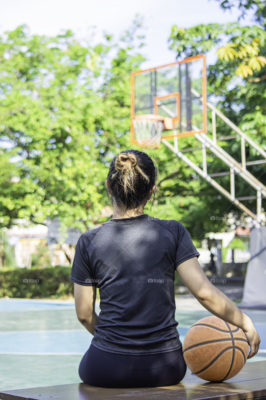 Basketball in hand Asian woman Background blur tree in park.