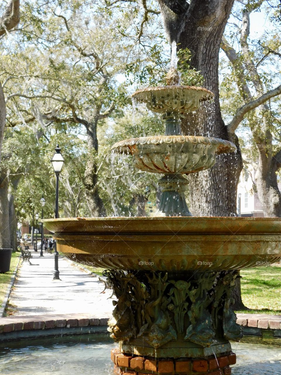 A fountain cheerfully bubbles and cascades down its tiers in a Charleston, SC park in the historic district.