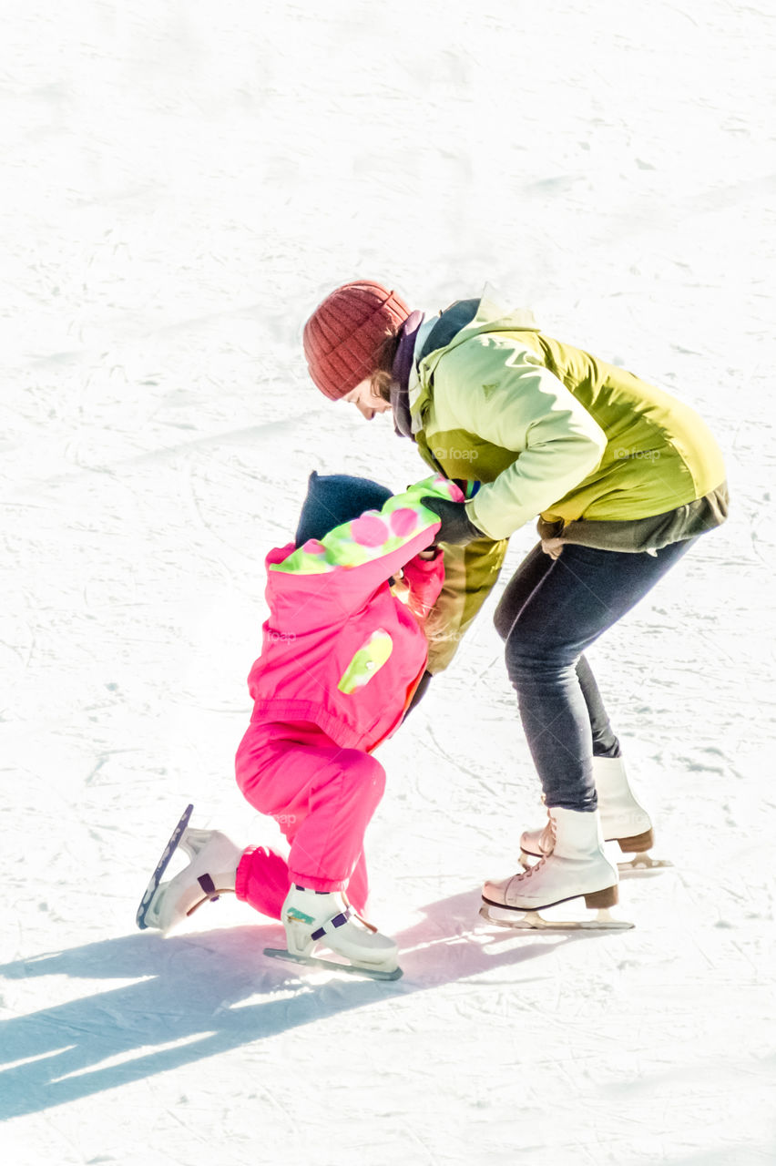 Mother Helps Her Child On Ice Skating Rink
