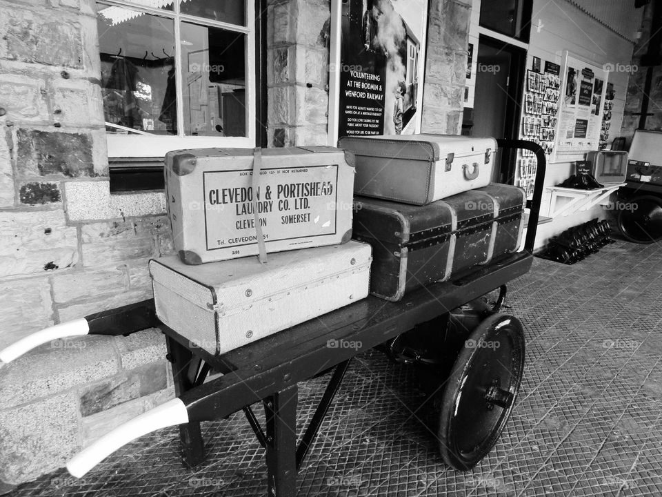 black and white photo of vintage luggage display at a railway station