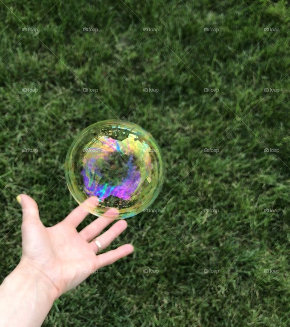 Hand reaching for a large bubble
