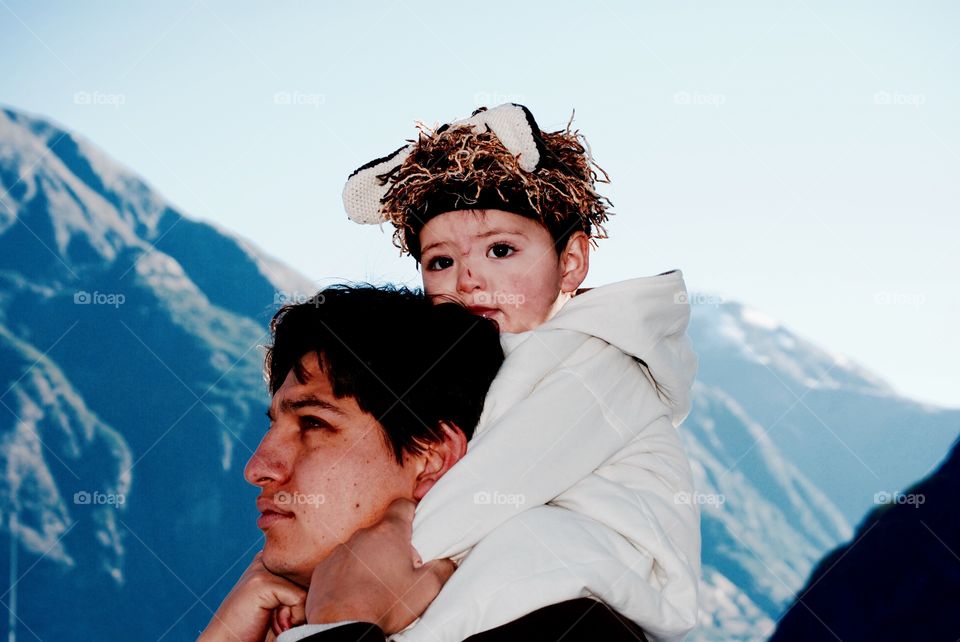 Cute girl on father shoulder against mountain