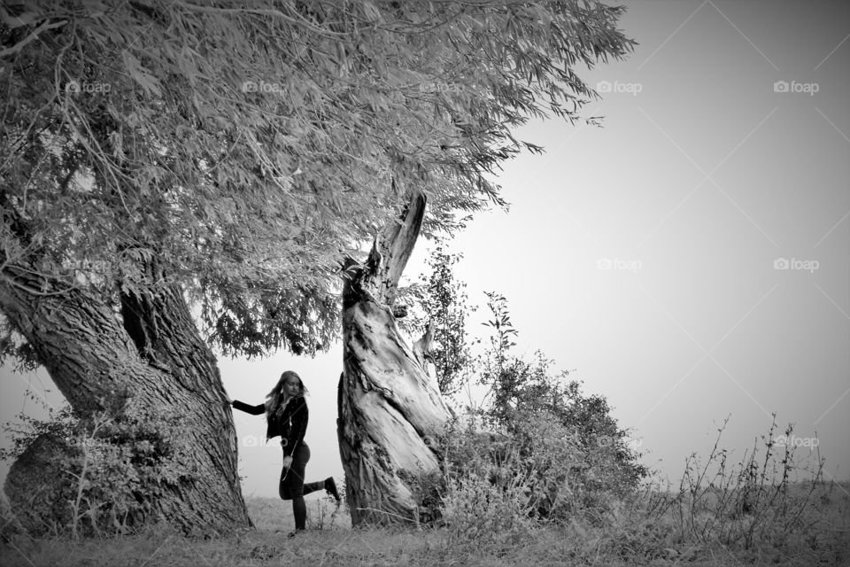 Girl leaning against an old tree in black and white