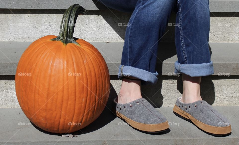 Woman sitting on porch next to an un-carved pumpkin