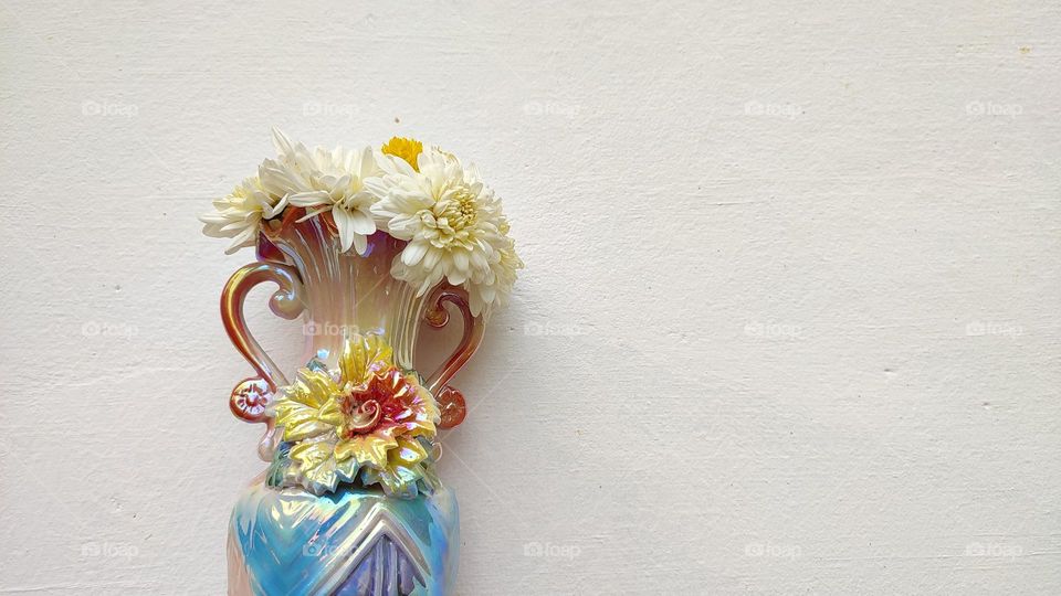 Beautiful white flowers in a colourful flowerpot with a flower sculpture, Flowers in a vase, colourful vase, white flowers in a vase