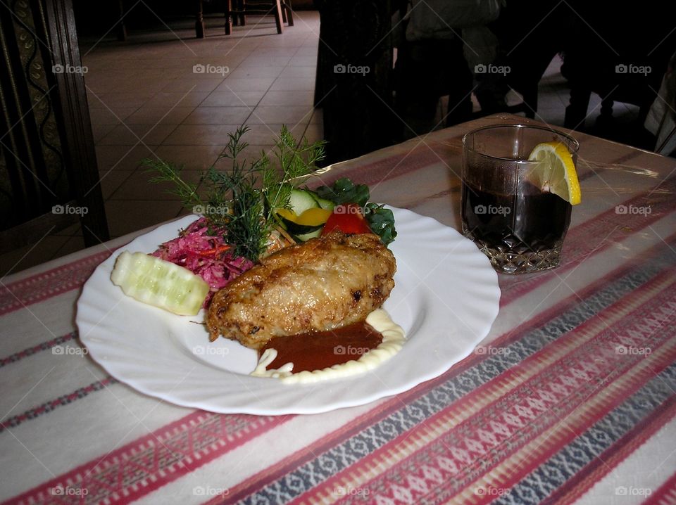 Meat with vegetables on a plate on a traditional Ukrainian stitched tablecloth