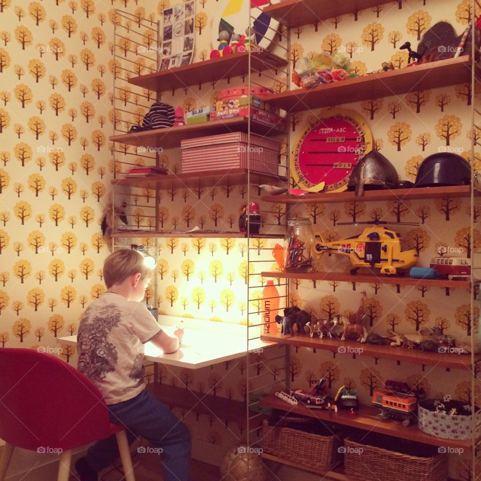 Boy doing homework in room with yellow wallpaper