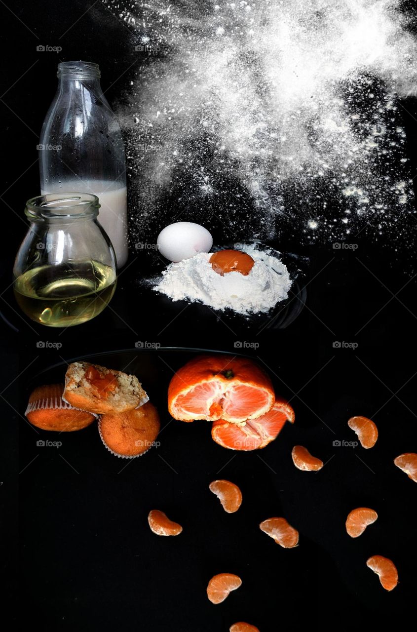 Photo flip.  Cooking tangerine cupcakes.  The black background is divided.  At the top are the ingredients: milk in a bottle, butter in a jar, white flour and an egg.  Bottom of cupcakes and tangerine slices