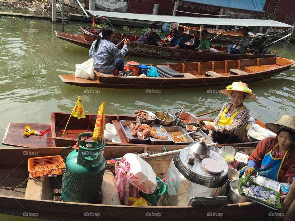 Peddling some food on her boat at Damnoen Saduak Floating Market, Bangkok