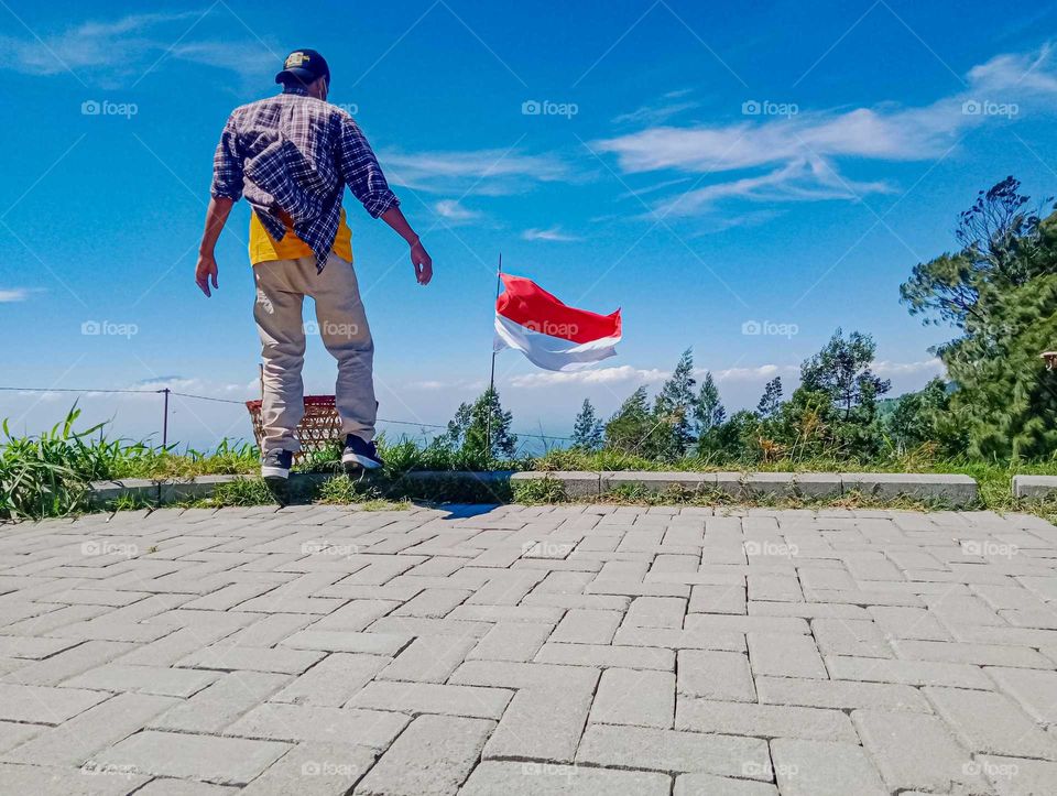 A man is approaching the red and white flag on Mount Merbabu, Central Java, Indonesia.