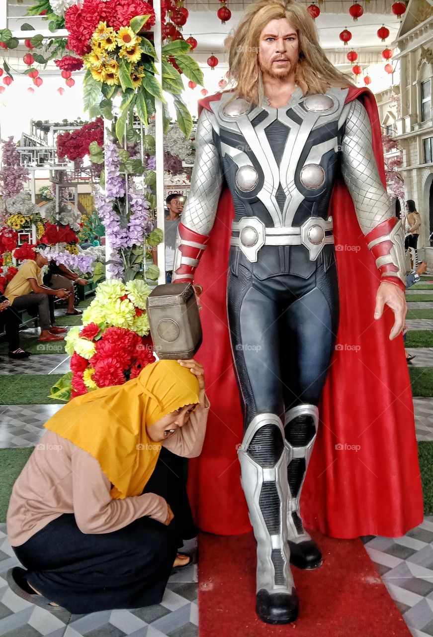 A woman is taking a photo in a funny pose with a wax statue.