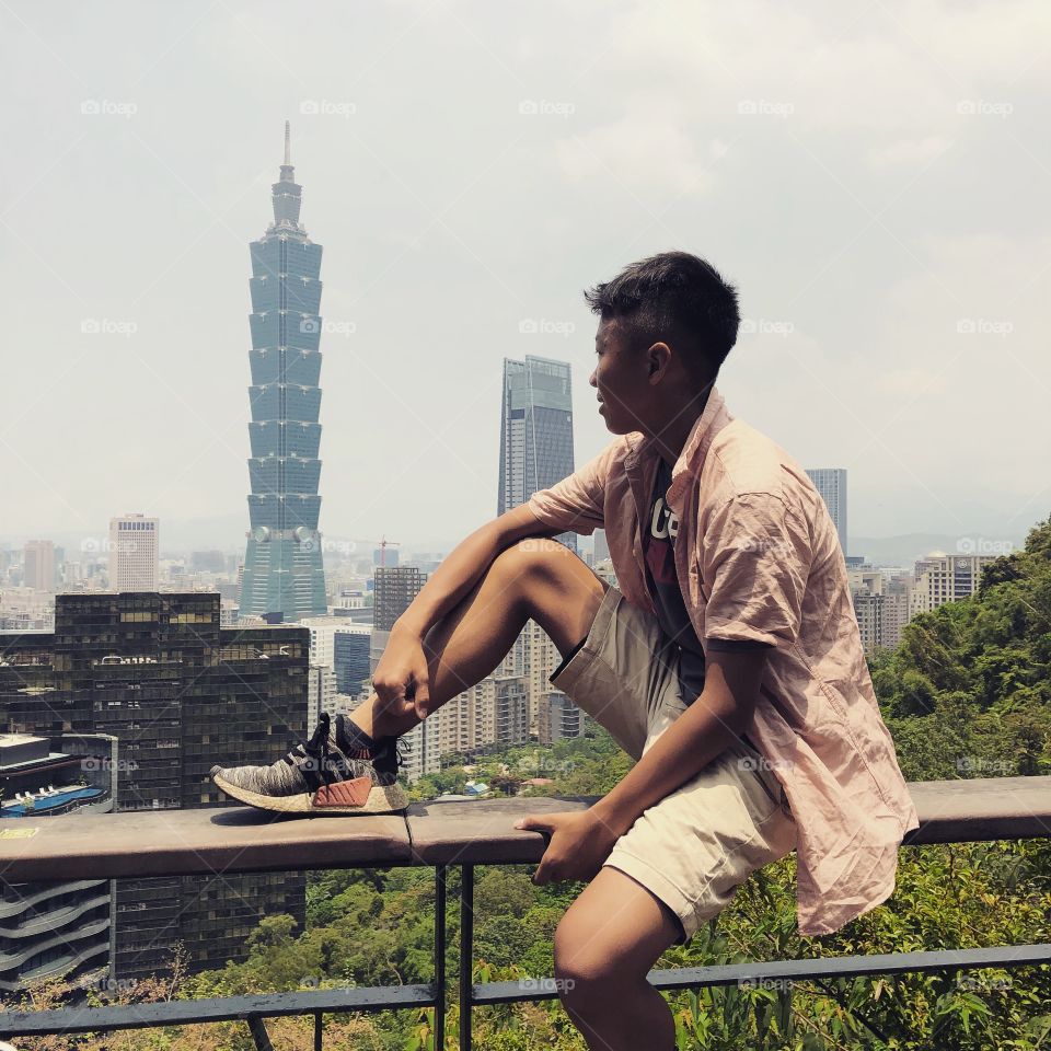 Sitting on top of a railing looking down at the beautiful Taipei City, Taiwan and the breathtaking Taipei 101. 