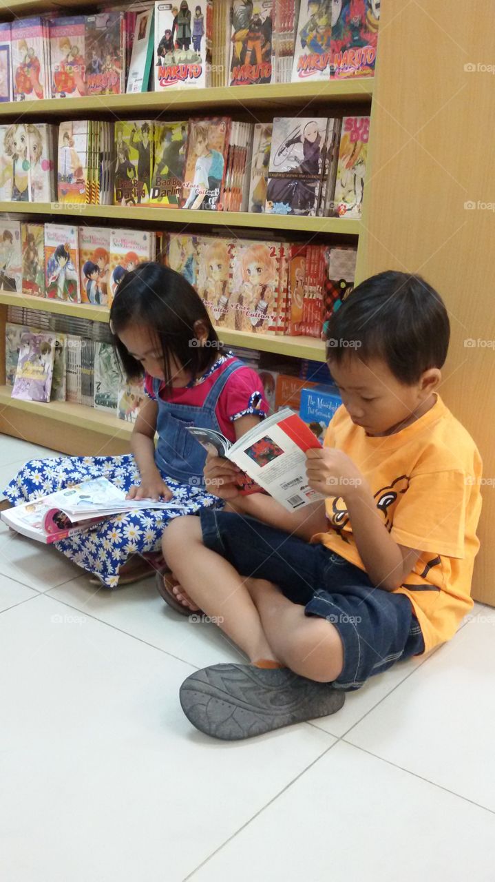 Sibling reading book in library